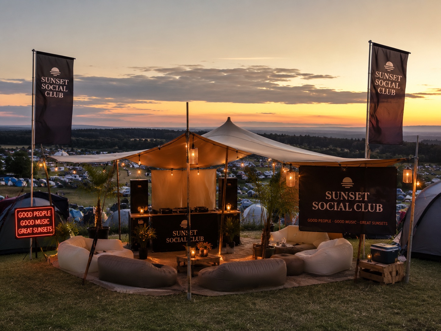 Das Sunset Social Club Camp bei Sonnenuntergang: Stretchzelt mit Lichterkette, DJ-Bar mit zwei JBL-Boxen, zwei Fahnen, großes Banner, Neonschild und Luft-Couches